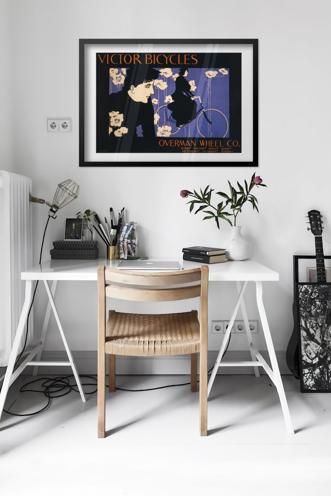 Victor Bicycles poster framed above a desk in a bright white room