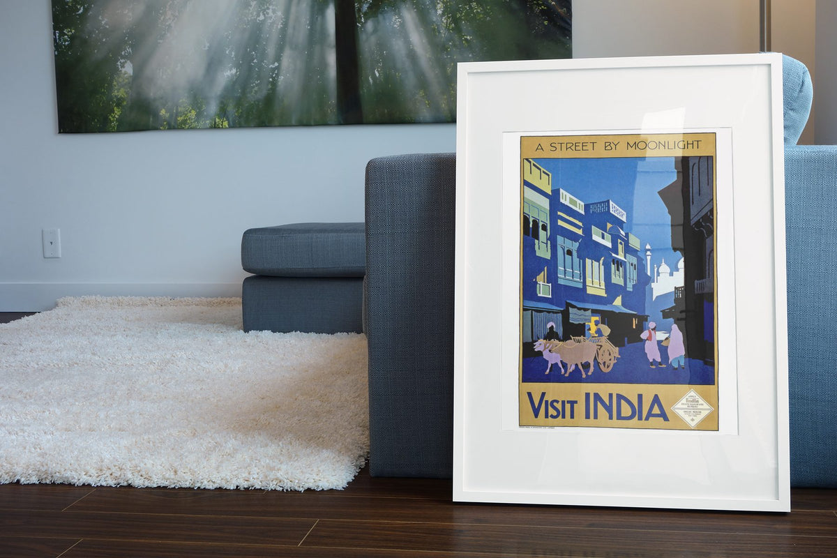 Visit India Street by Moonlight poster leaning beside a blue sofa