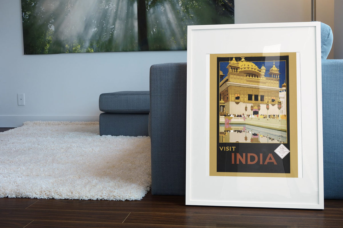 Visit India Golden Temple poster leaning beside a blue sofa