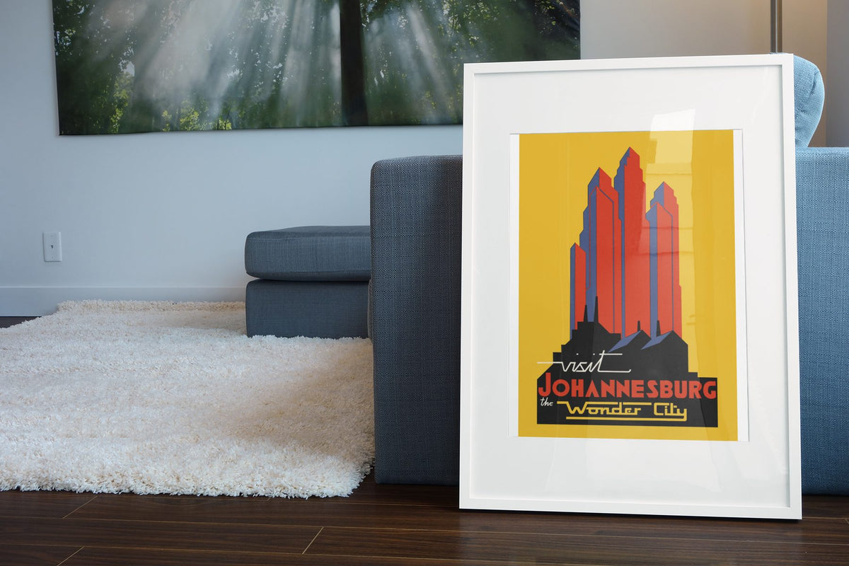 Visit Johannesburg poster leaning beside a blue sofa