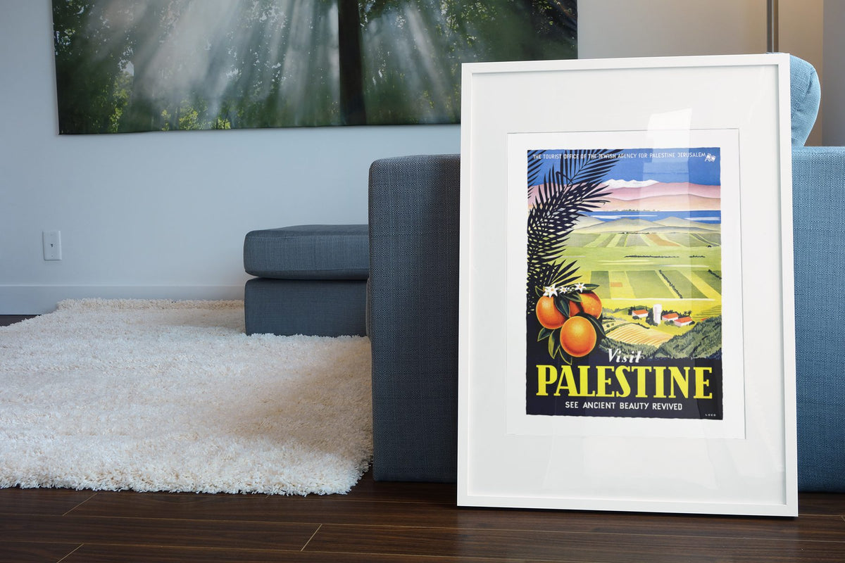 Visit Palestine Ancient Beauty Revived poster leaning beside a blue sofa