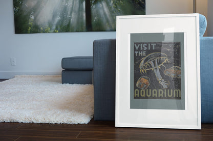Visit the Aquarium Jellyfish poster leaning beside a blue sofa