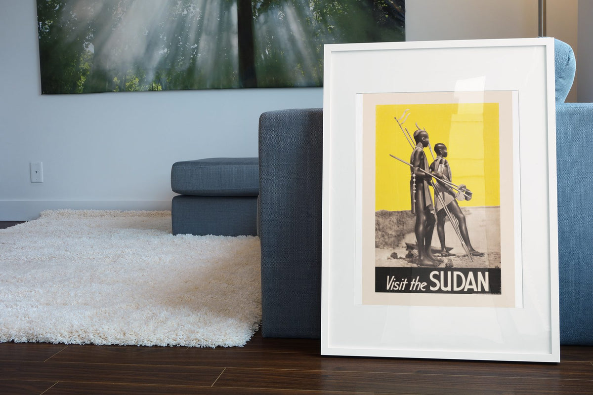Visit the Sudan poster leaning beside a blue sofa
