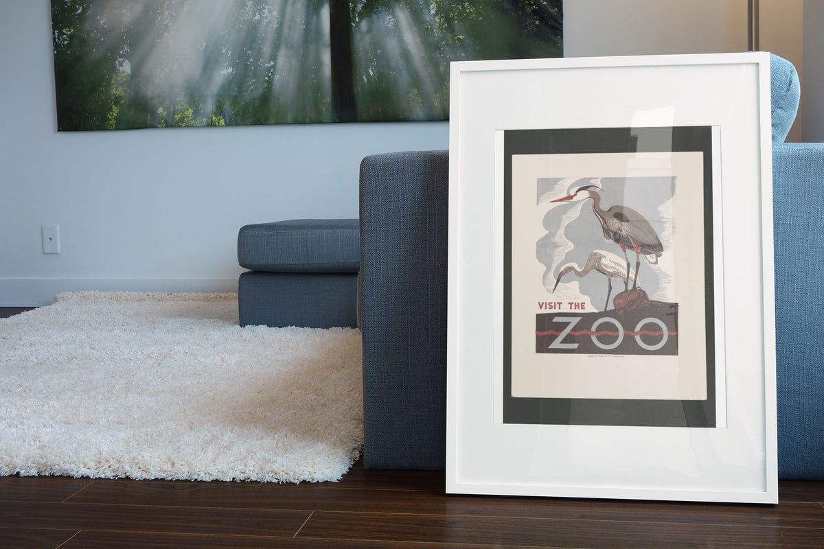 Visit the Zoo Herons poster leaning beside a blue sofa