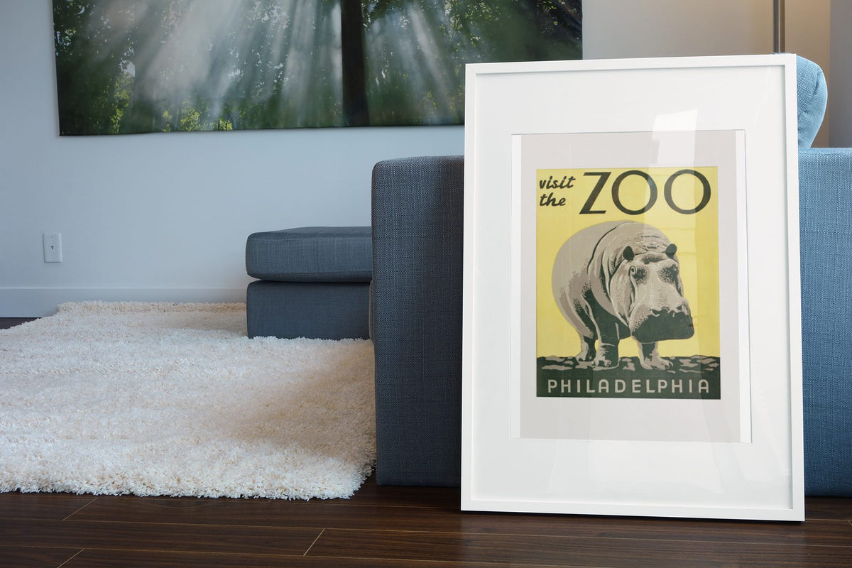 Visit the Zoo Philadelphia Hippo poster leaning beside a blue sofa