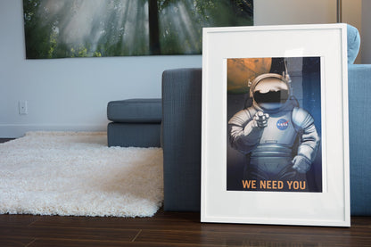 We Need You on Mars NASA recruitment poster in a white frame leaning beside a blue sofa