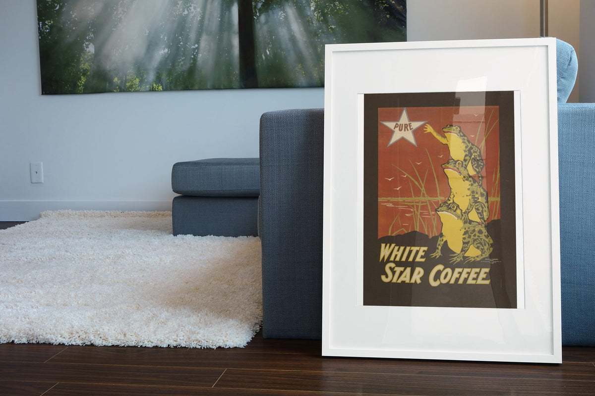 White Star Coffee Frogs poster leaning beside a blue sofa