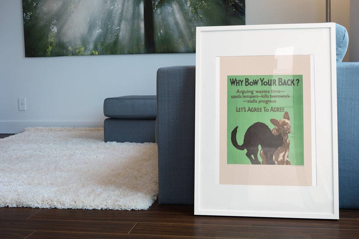 Why Bow Your Back poster in a white frame leaning beside a blue sofa