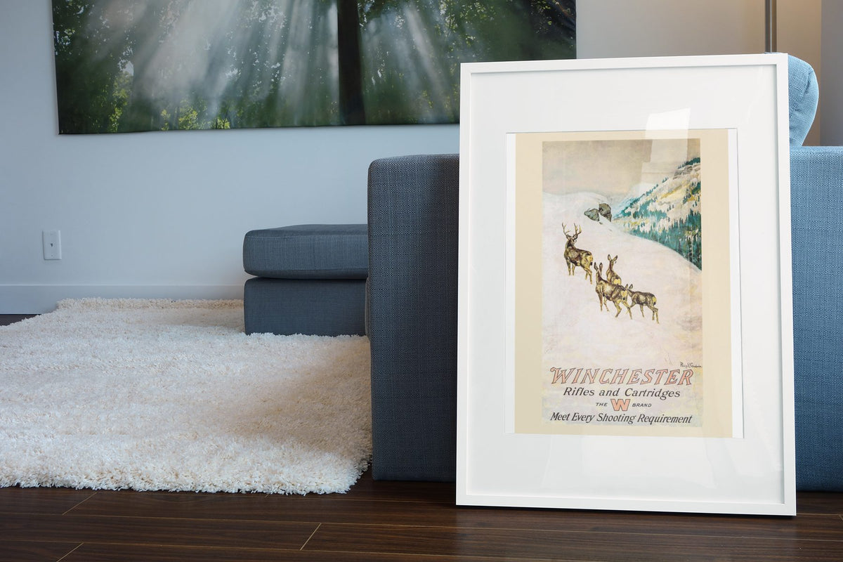 Winchester Rifles and Cartridges — Deer poster leaning beside a blue sofa