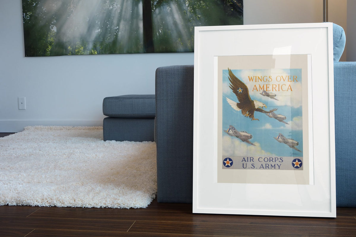 Wings Over America Air Corps US Army poster leaning beside a blue sofa