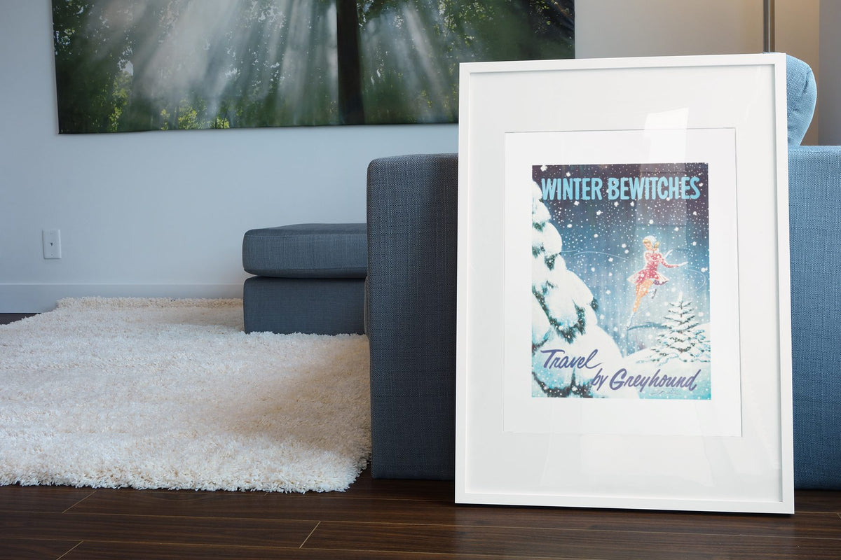 Winter Bewitches Greyhound poster leaning beside a blue sofa
