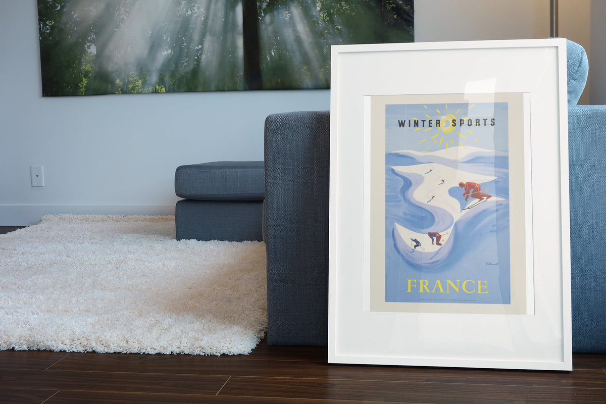 Winter Sports France poster leaning beside a blue sofa