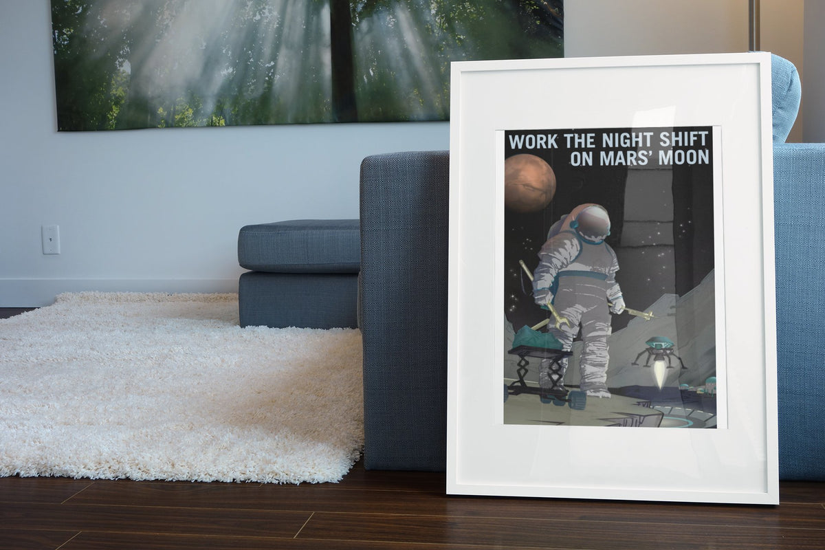 Work the Night Shift on Mars' Moon poster in a white frame leaning beside a blue sofa