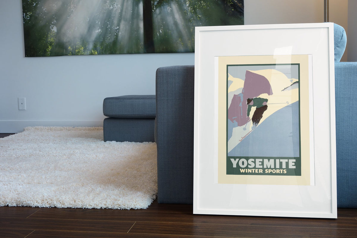 Yosemite Winter Sports Half Dome poster leaning beside a blue sofa