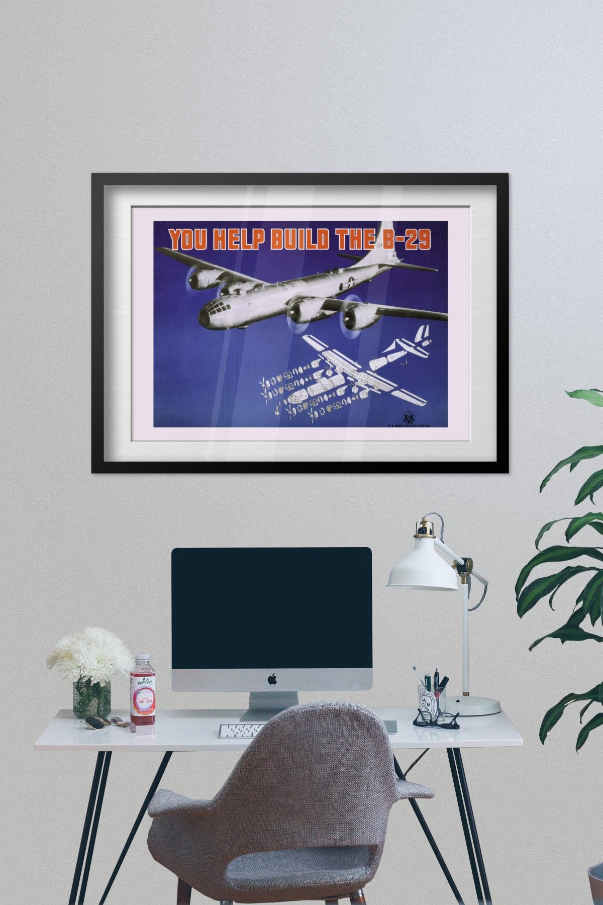 You Help Build the B-29 poster framed on a grey wall above a desk