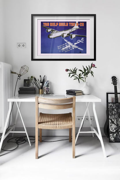 You Help Build the B-29 poster framed above a desk in a bright white room