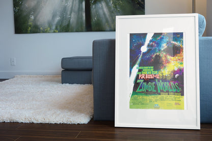 Zombie Worlds, NASA Galaxy of Horrors poster in a white frame leaning beside a blue sofa